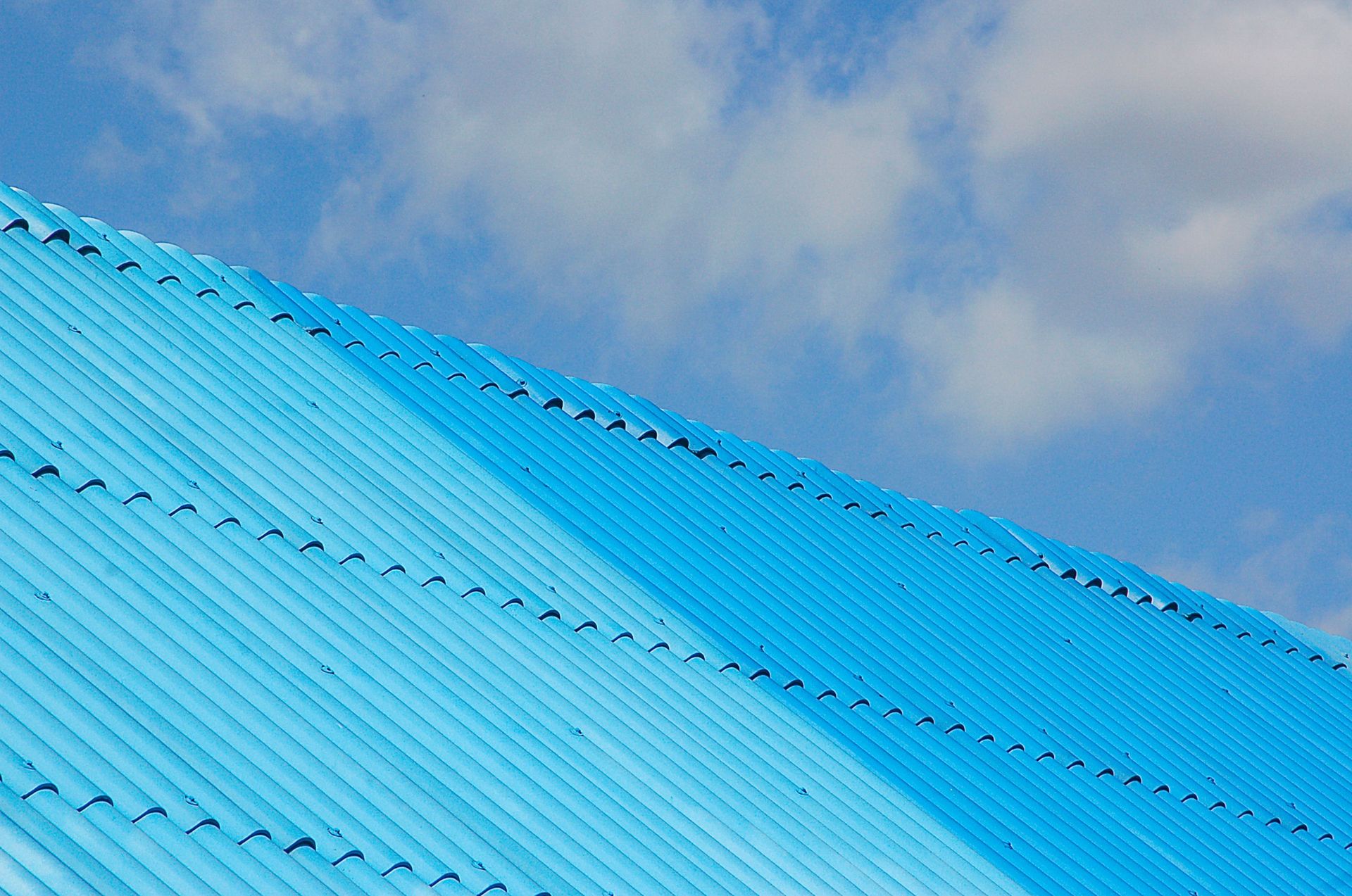 A bright blue corrugated roof shot from a low angle against a clear sky.